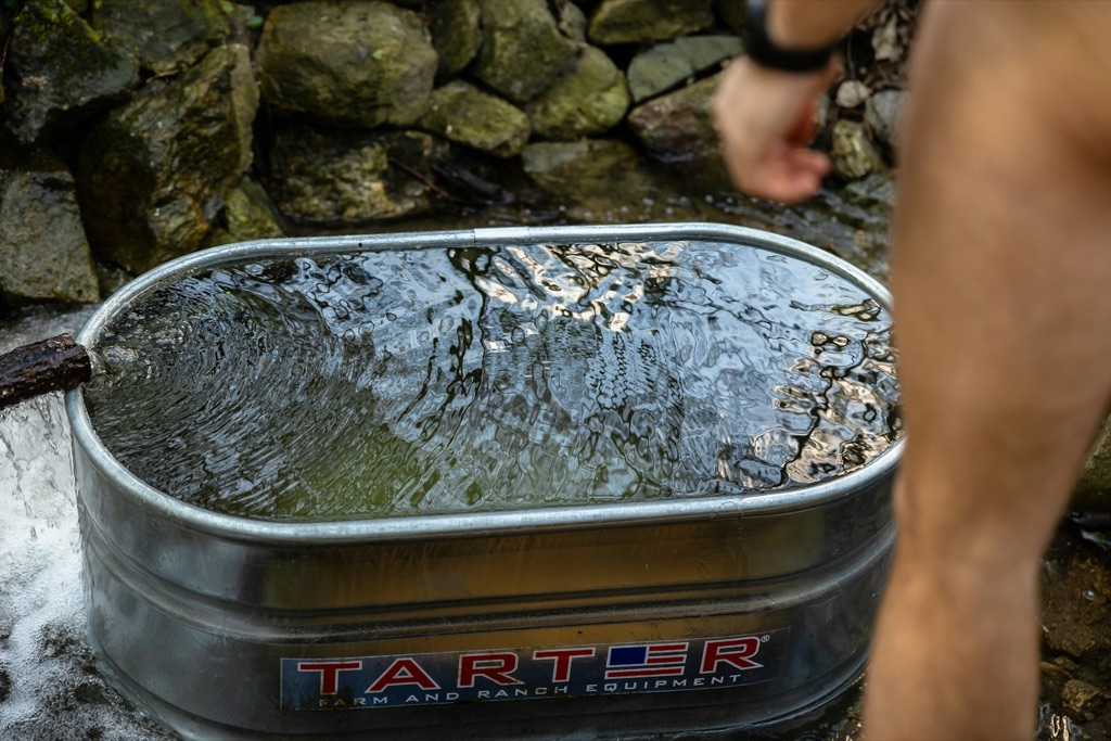 Man kliver fram till ett metallkar fyllt med kallt vatten för ett kallbad utomhus.